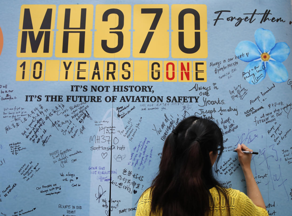 Una mujer escribe un mensaje en un panel durante un acto para conmemorar los 10 años de la desaparición del vuelo MH370 de Malaysia Airlines, en un centro comercial en Subang Jaya, en las afueras de Kuala Lumpur, Malasia, el domingo 3 de marzo de 2024. (AP Foto/FL Wong)