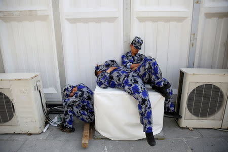 Security personnel take a nap behind one of the halls of Auto China 2016 auto show in Beijing April 25, 2016. REUTERS/Damir Sagolj/File Photo