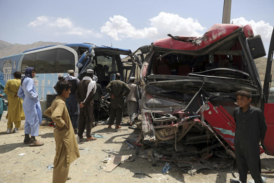 People stand near damaged buses after a deadly accident on the Kabul-Kandahar highway, on the outskirts of Kabul, Afghanistan, Tuesday, April 27, 2021. Two buses crashed head-on near Kabul, killing several people and injuring more than 70, an Afghan official said Tuesday. (AP Photo/Rahmat Gul)