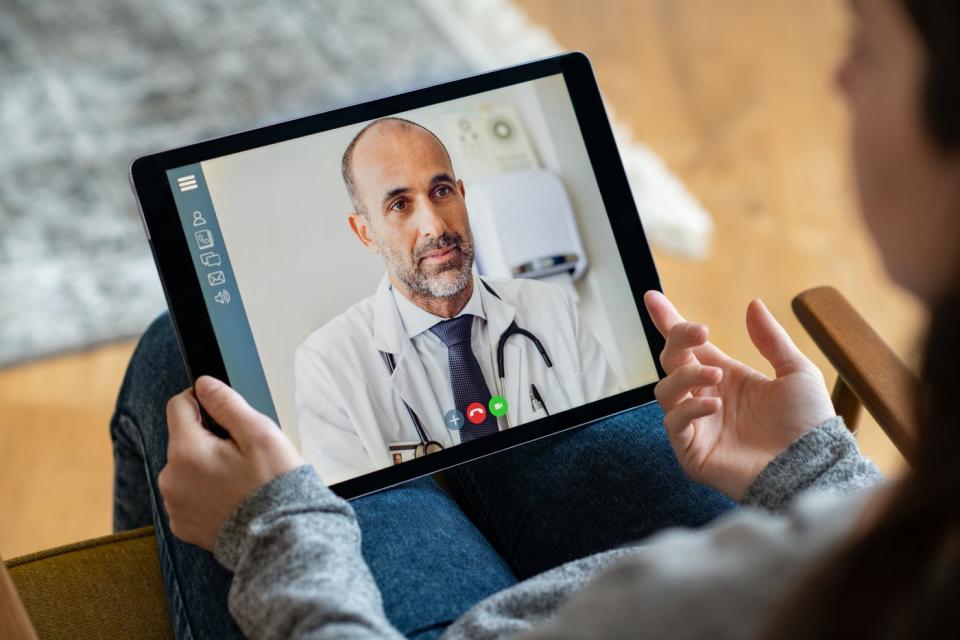 a person holding an ipad with a doctor on video chat