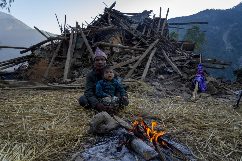 A man and a child sit in front of earthquake damaged house in Jajarkot district, northwestern Nepal, Sunday, Nov. 5, 2023. Most of the houses in villages in Jajarkot district either collapsed or were severely damaged by the sudden earthquake Friday night, while the few concrete houses in towns were also damaged. (AP Photo/Niranjan Shrestha)