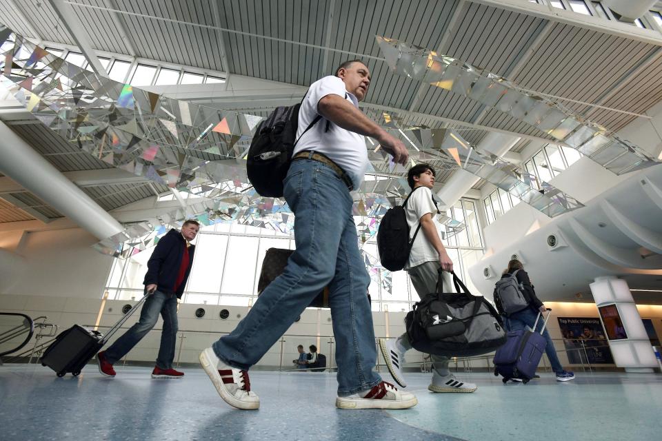 Passengers make their way past suspended artwork through the terminal at Jacksonville International Airport after arriving on their flights Thursday. The Jacksonville Aviation Authority announced that 2023 was a record year for passengers with 7,446,084.