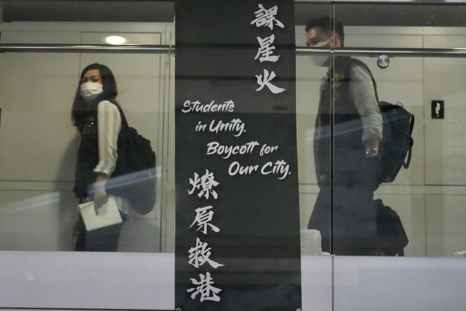 Police officers walk across a banner at the office of student union in campus of the University of Hong Kong, Friday, July 16, 2021. Hong Kong's national security police on Friday raided the office after student leaders last week commemorated the death of an attacker who killed himself after stabbing a police officer. (AP Photo/Kin Cheung)