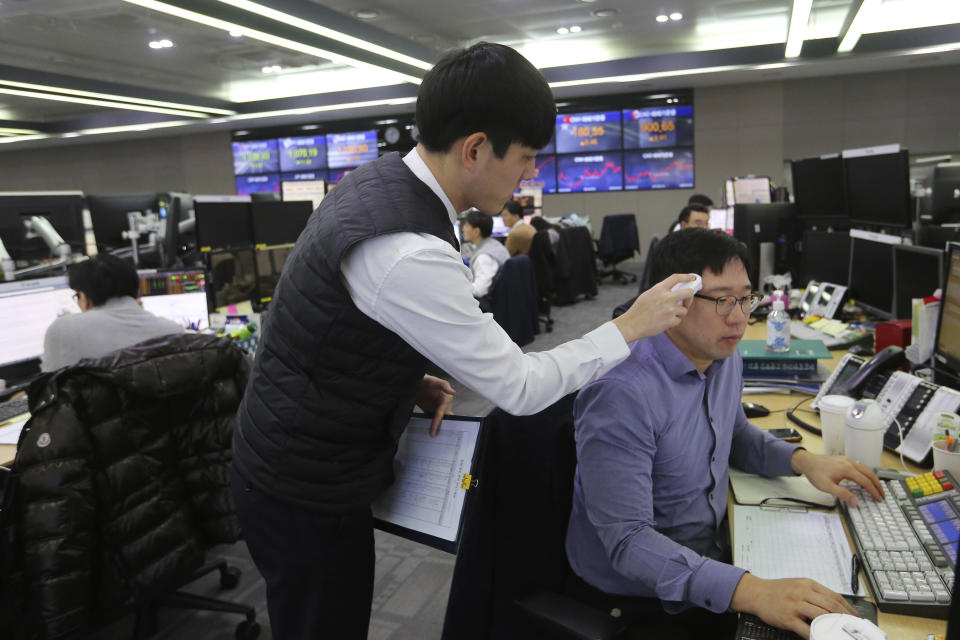 A currency trader checks the temperature of his colleague at the foreign exchange dealing room of the KEB Hana Bank headquarters in Seoul, South Korea, Thursday, Feb. 20, 2020. Asian shares were mixed Thursday after Wall Street recovered to record highs, but worries continued about the damage to the regional economy from the new virus that began in China. (AP Photo/Ahn Young-joon)