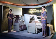 A Singapore Airlines (SIA) stewardesses stand next to a display of the new Singapore Airlines Business Class seats during their next generation cabin product launch in Singapore on July 9, 2013. SIA on July 9 unveiled new seats and other in-flight amenities as part of a sweeping upgrade of its cabins amid intensifying competition in the industry. AFP PHOTO / ROSLAN RAHMAN