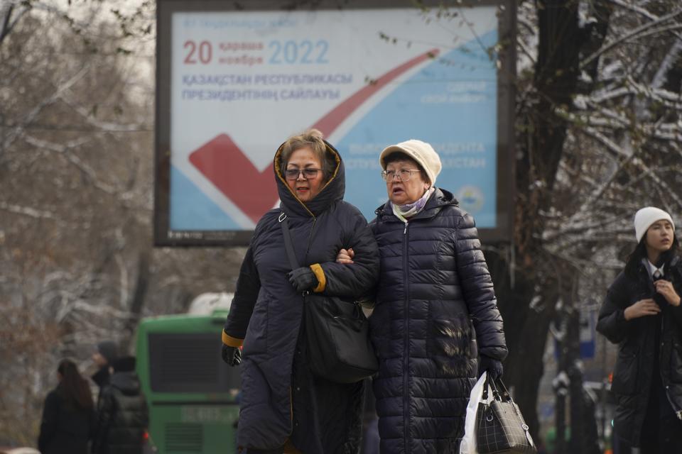 People walk down a street with an election poster in the background in Almaty, Kazakhstan, Thursday, Nov. 17, 2022. Kazakhstan's president, who faced a bloody outburst of unrest early this year and then moved to marginalize some of the Central Asian country's longtime powerful figures, appears certain to win a new term against little-known challengers in a snap election on Sunday. (Vladimir Tretyakov/NUR.KZ via AP)