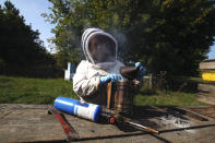 Beekeeper Samantha Jones prepares a bee smoker near hives kept near Iola, Wis., on Wednesday, Sept. 23, 2020. Among other things, the smoke helps calm the bees so beekeepers can open the hives. Jones and her husband, James Cook, have worked with honey bees for several years but started their own business this year — and proceeded with plans even after the coronavirus pandemic hit. (AP Photo/Carrie Antlfinger)