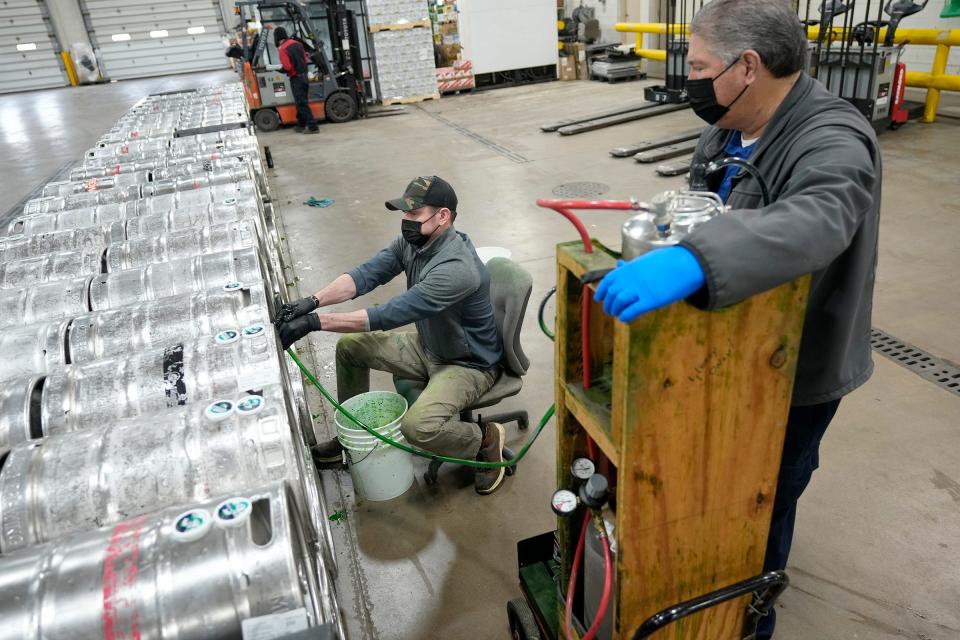 Sales-service manager Ryan Mallery (left) feeds green food coloring into a keg as technician Jerry Wucinski controls the amount that’s added as part of the process of making green beer on March 6 at Beer Capitol Distributing in Sussex.