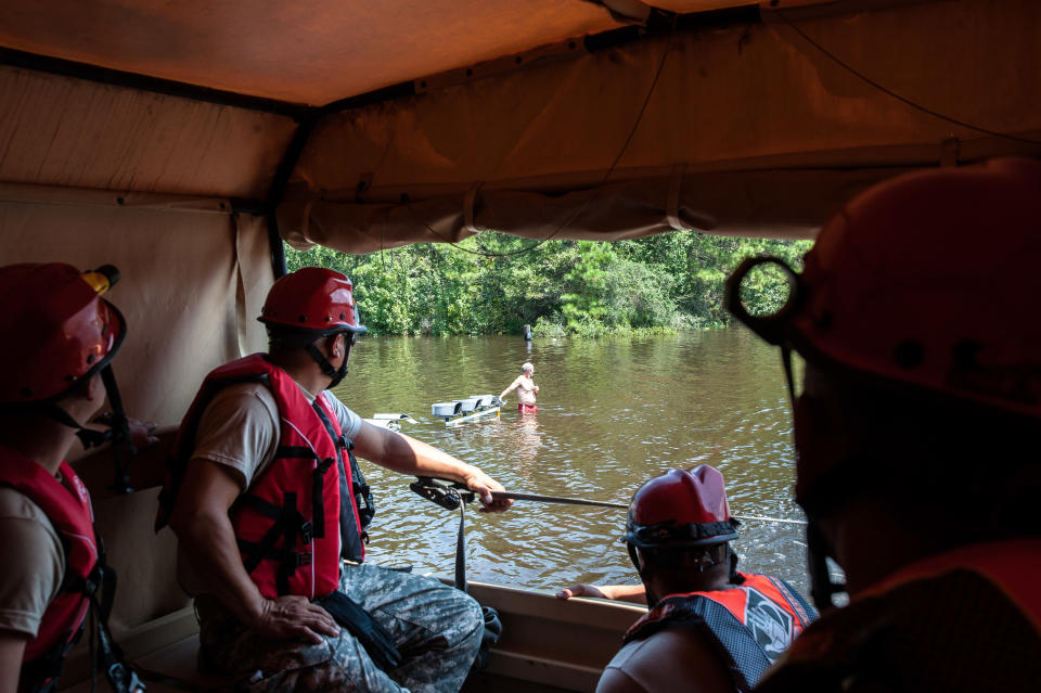 The National Guard convoy drives past a man waiting for pick up from the next boat in a flooded town in East Texas on Friday.