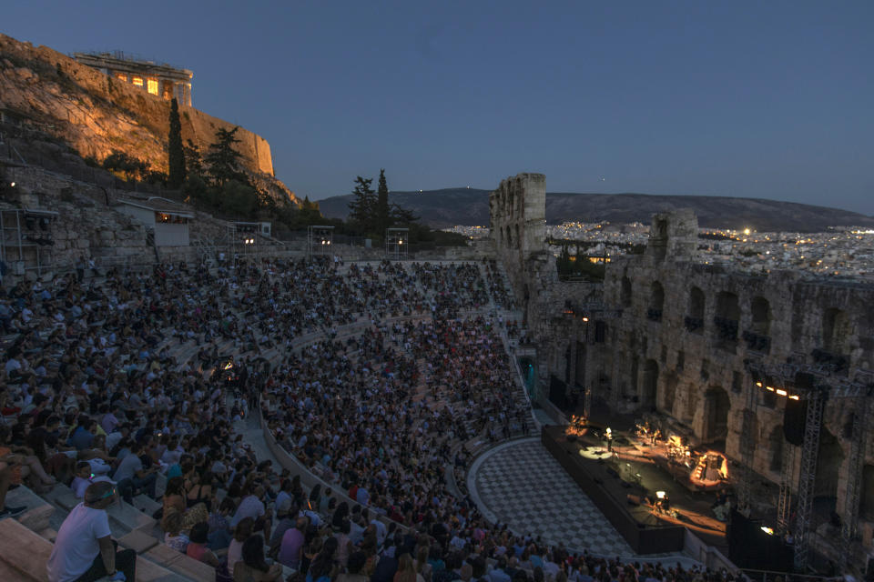 Actors and singers perform at the Odeon of Herodes Atticus in Athens, Greece, after the site was reopened for performances on Wednesday, July 15, 2020, with the ancient Parthenon temple in the background. Seating limits have been imposed at the renovated ancient stone Roman theater, underneath the Acropolis, as part of the restrictions due to the COVID-19 pandemic. Authorities allowed the venue to reopen despite recently canceling some other summer events to avoid crowding.(AP Photo/Petros Giannakouris)