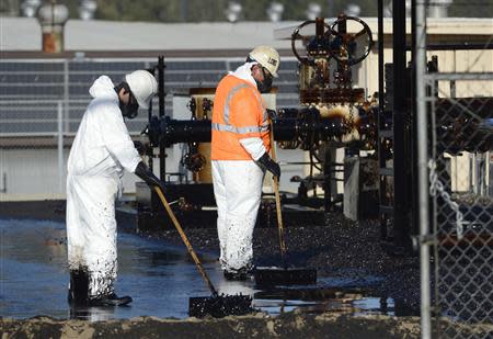 Workers clean up spilled oil at a facility in Los Angeles, May 15, 2014. REUTERS/Phil McCarten