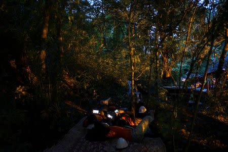 Rescue workers use mobile phones as they take a short break near the Tham Luang cave, where 12 boys and their soccer coach are trapped, in the northern province of Chiang Rai, Thailand, July 6, 2018. REUTERS/Athit Perawongmetha
