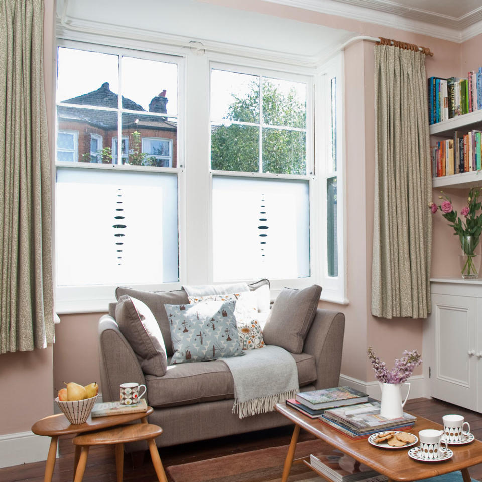 small living room with sofa throw and patterned cushions with wooden coffee table and white wall mounted sideboard