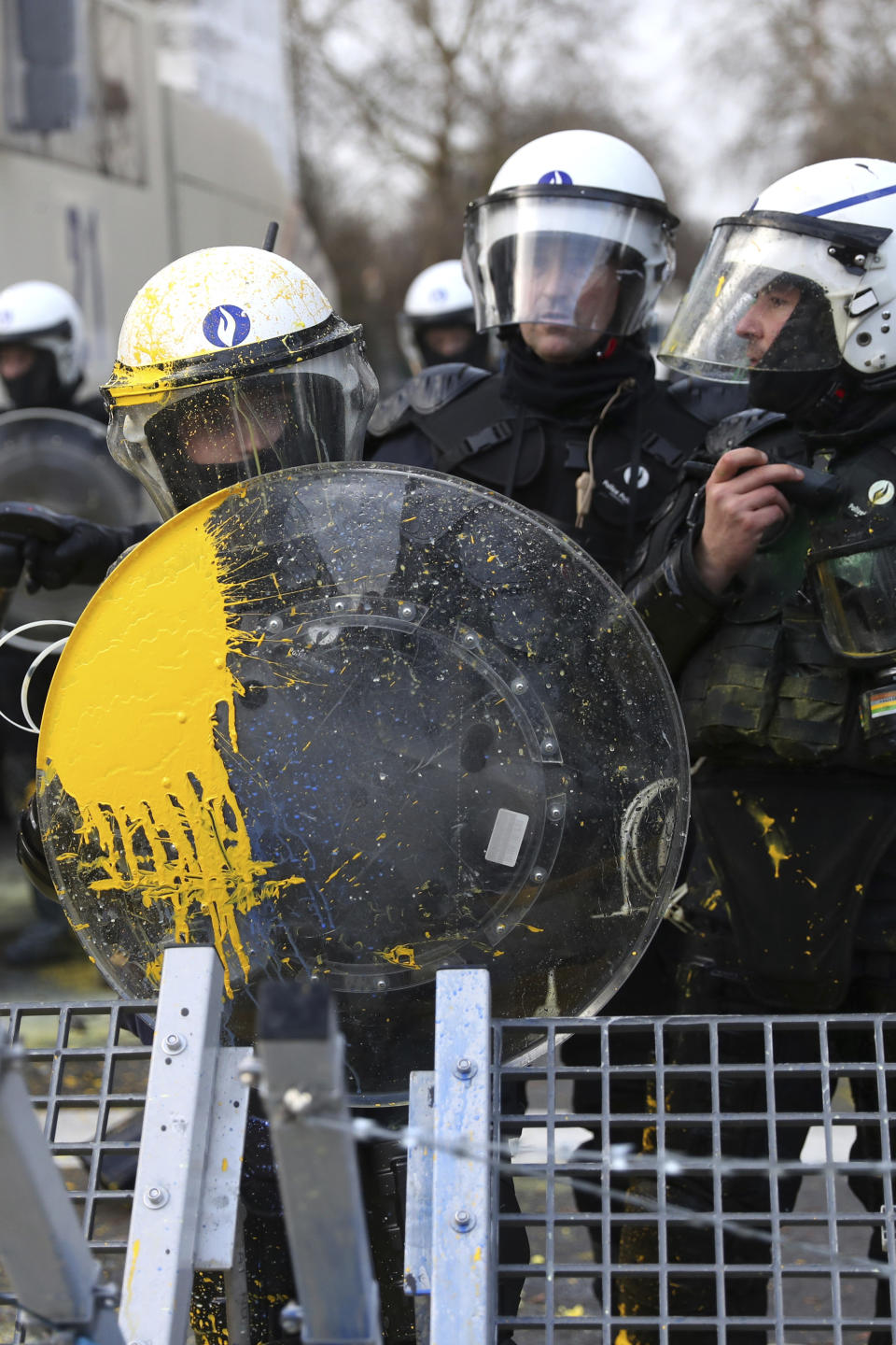 A police officer holds a shield covered with yellow paint during a demonstration in Brussels, Saturday, Dec. 8, 2018. Hundreds of police officers are being mobilized in Brussels Saturday, where yellow vest protesters last week clashed with police and torched two police vehicles. More than 70 people were detained. (AP Photo/Francisco Seco)