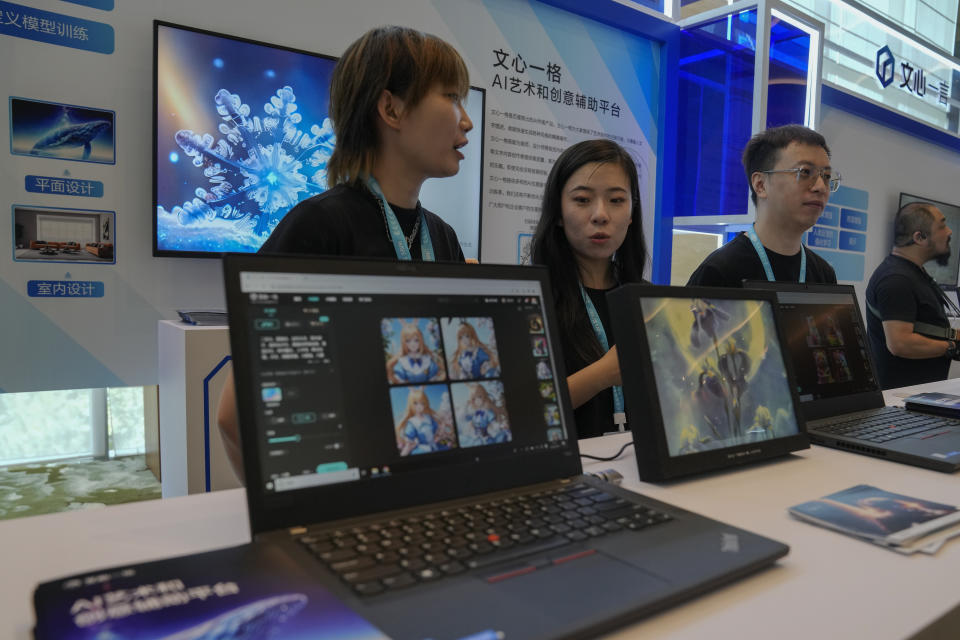 Staff members chat each other at a booth promoting the AI chatbot Ernie Bot during the Wave Summit in Beijing on Aug. 16, 2023. Chinese search engine and artificial intelligence firm Baidu on Thursday made its ChatGPT-equivalent language model available to the public, in a sign of a green light from Beijing which has in recent months taken steps to regulate the industry. (AP Photo/Andy Wong)