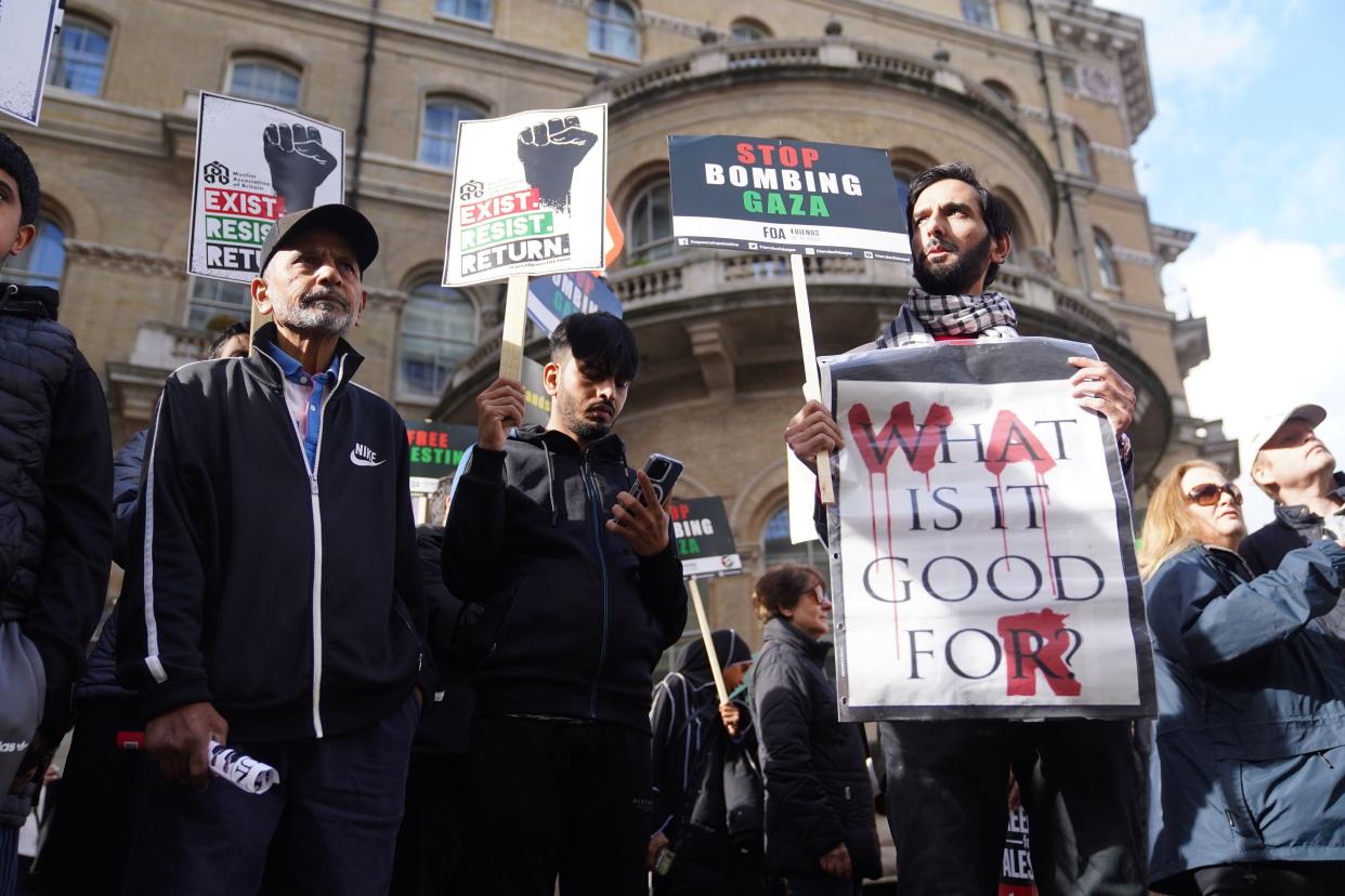 Three men stand with placards at a pro-Palestine rally in London. One placard reads ‘Stop bombing Gaza' (PA)
