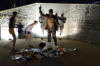 People visit the Joe Paterno statue early Sunday July 22, 2012. in State College, Pa. The famed statue of Paterno was taken down from outside the Penn State football stadium Sunday morning, eliminating a key piece of the iconography surrounding the once-sainted football coach accused of burying child sex abuse allegations against a retired assistant. (AP Photo/John Beale)