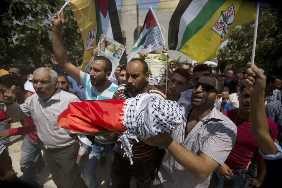 FILE - Palestinians carry the body of 18-month-old Ali Dawabsheh during his funeral in the West Bank village of Duma on July 31, 2015. The sleeping toddler was burned to death when Jewish assailants set fire to two Palestinian homes, an attack that also killed his parents and critically wounded his 4-year-old brother. An Israeli group raising funds for Jewish radicals convicted in some of the country’s most notorious hate crimes, including the Duma attack, is collecting tax-exempt donations from Americans, according to an investigation by the AP and the Israeli investigative platform Shomrim. (AP Photo/Mahmoud Illean, File)