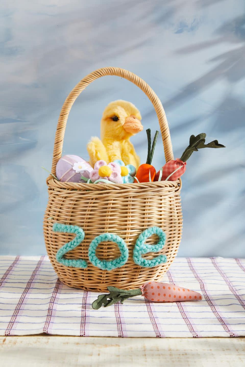 an easter basket with a diy name on the front made from braided yarn filled with easter toys