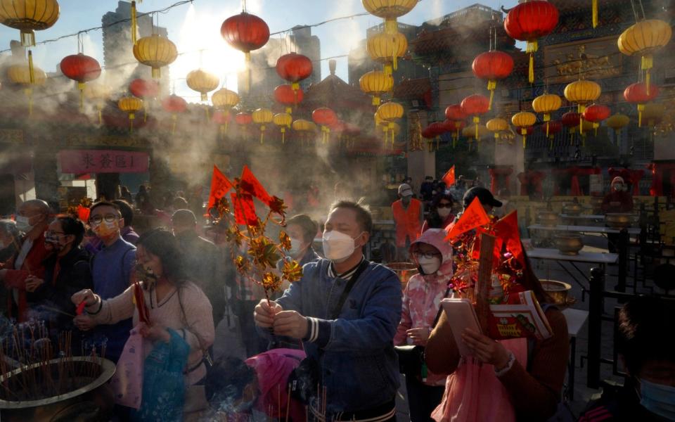 Worshippers wearing face masks burn joss sticks as they pray at the Wong Tai Sin Temple, in Hong Kong, to celebrate the Lunar New Year - AP Photo/Kin Cheung