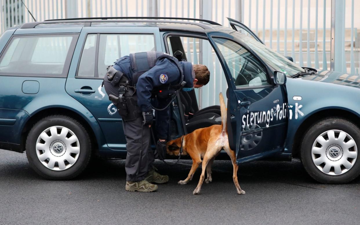 Police with a sniffer dog searches a car which crashed into the main gate of the chancellery in Berlin - FABRIZIO BENSCH /REUTERS 