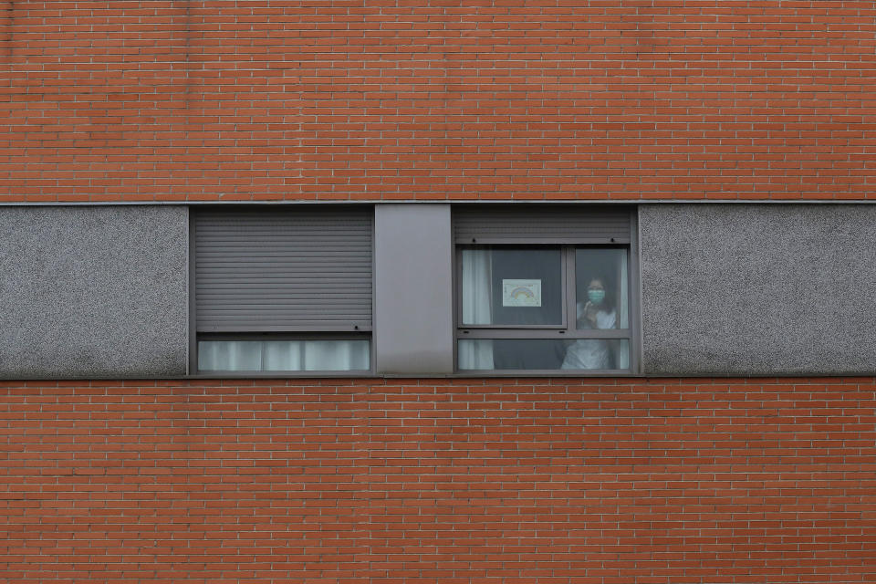 A nurse looks out from a window inside of a nursing homes where dead bodies were found at the nursing homes of Usera in Madrid, Spain, Tuesday, March 24, 2020. Spanish army troops disinfecting nursing homes have found, to their horror, some residents living in squalor among the infectious bodies of people that authorities suspect have died from the new coronavirus. Prosecutors have launched a judicial probe. For some, it can cause more severe illness, especially in older adults and people with existing health problems. (AP Photo/Manu Fernandez)