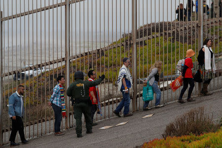 A U.S. Customs and Border Protection (CBP) official detains people during a gathering in support of the migrant caravan in San Diego, U.S., close to the border wall between the United States and Mexico, as seen from Tijuana, Mexico December 10, 2018. REUTERS/Carlos Garcia Rawlins