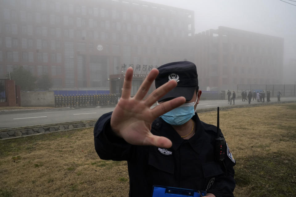 A security guard tries to cover a camera outside the Wuhan Institute of Virology. 