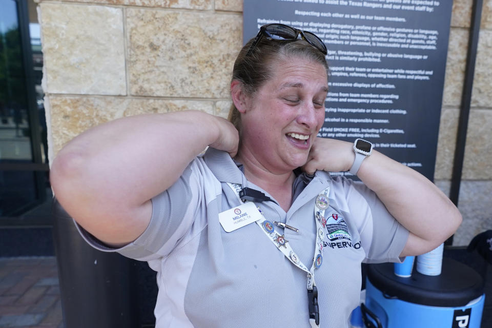 Melanie, no last name given, reacts to putting a cold towel on her neck while working security outside the ballpark in Arlington, Texas, Monday, June 26, 2023. (AP Photo/LM Otero)