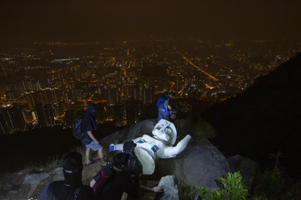 Anti-government protesters carry a part of the four-meter statue "The Lady Liberty of Hong Kong", that symbolizes the city's recent democratic movement, was brought to Lion Rock, one of Hong Kong's iconic peak, in Hong Kong, Sunday, Oct. 13, 2019. (AP Photo/Kin Cheung)