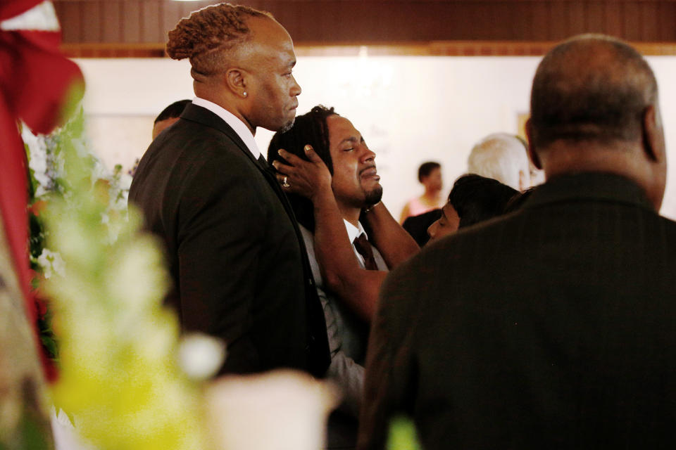 A relative attempts to console Dion Green, center, before the funeral for his father, Derrick Fudge, on Saturday, Aug. 10, 2019, at a church in Springfield, Ohio. Fudge, 57, was the oldest of nine who were killed when a gunman opened fire outside a bar early Sunday in Dayton, Ohio. (AP Photo/Angie Wang)