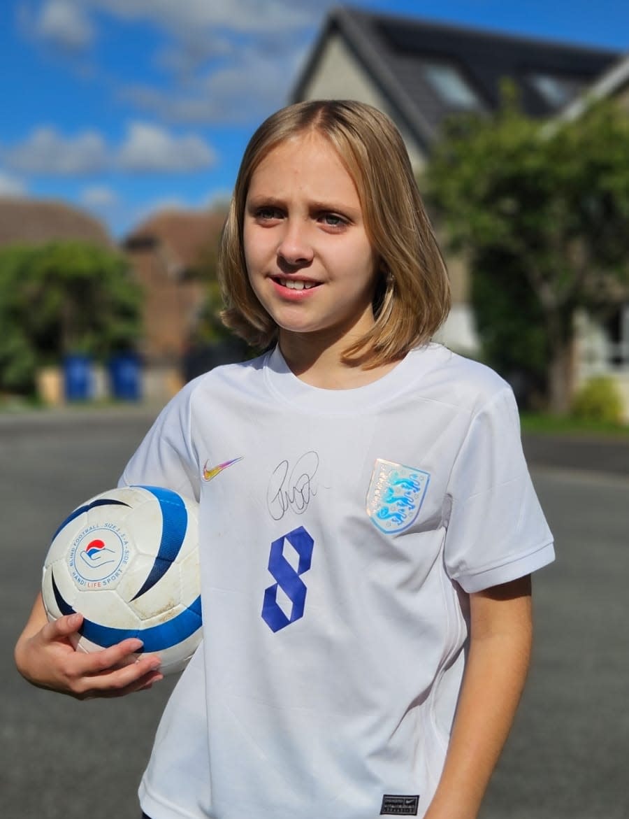 Caitlin Passey posing with ball under her arm 