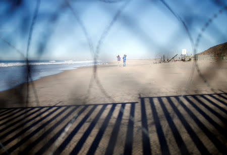 Mexican man Juan Castillo Esposo, standing with his son at International Friendship Park, in San Diego, U.S., is seen through the border fence as he looks at his wife Claudia Alvarez at the border wall in the city of Tijuana, Mexico December 8, 2018. Picture taken from Tijuana, Mexico. According to Alvarez, she has been trying to obtain a visa to U.S. for five years to live with her husband and son but her visa applications were refused. REUTERS/Mohammed Salem