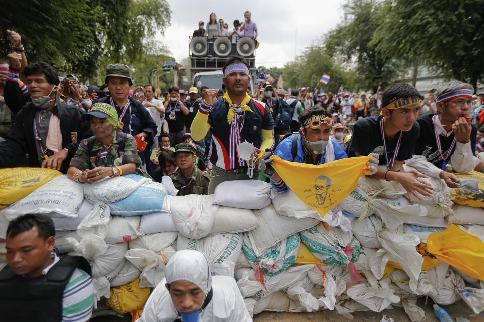 Anti-government protesters gesture towards policemen coming close to their barricade near the Government House in Bangkok