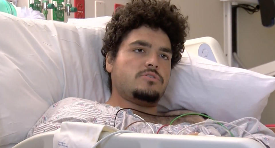 Jordan Riveria can be seen lying in a hospital bed with wires attached to him. 