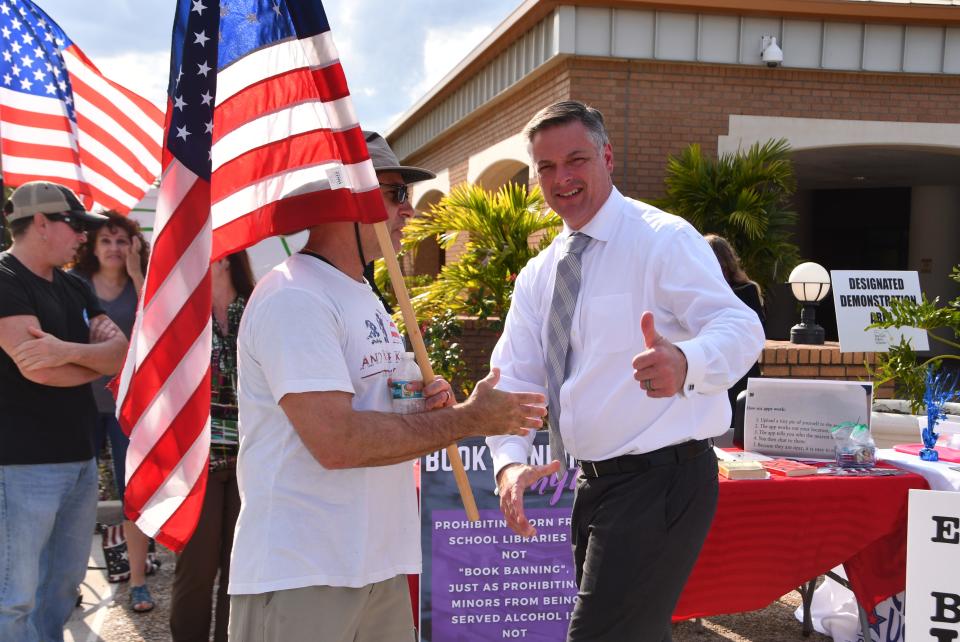 Brevard School Board Chair Matt Susin greets protesters waving flags outside before the March 28 school board meeting.