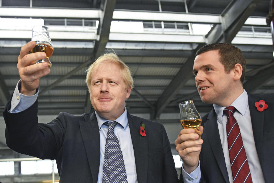 FILE - In this file photo dated Nov. 7, 2019, showing Britain's Prime Minister Boris Johnson alongside Douglas Ross, parliamentary under-secretary of state for Scotland, right in Moray, Scotland. Junior British government minister Douglas Ross has quit Tuesday May 26, 2020, over Prime Minister Boris Johnson’s failure to fire his top aide Dominic Cummings for allegedly breaching COVID-19 coronavirus lockdown rules. (Stefan Rousseau / PA via AP)