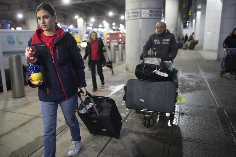 In this Tuesday, Dec. 3, 2019, photo Mohammed Hafar, right, helps his daughter Jana Hafar with her luggage as they leave JFK Airport in New York. Jana had been forced by President Donald Trump's travel ban to stay behind in Syria for months while her father, his wife and son Karim started rebuilding their lives in Bloomfield, N.J., with no clear idea of when the family would be together again. (AP Photo/Mary Altaffer)