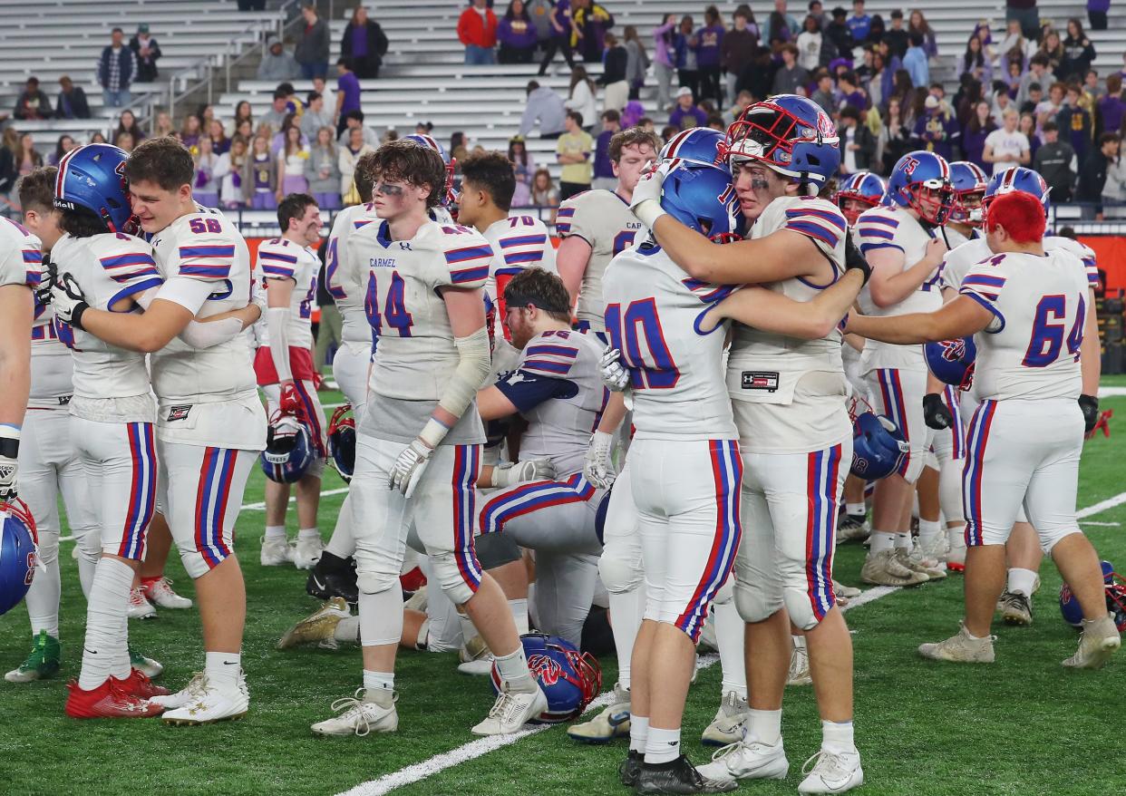Carmel players console each other after Christian Brothers Academy defeated them 31-14 in the New York State Class AA championship at the JMA Dome in Syracuse Dec. 3, 2023.