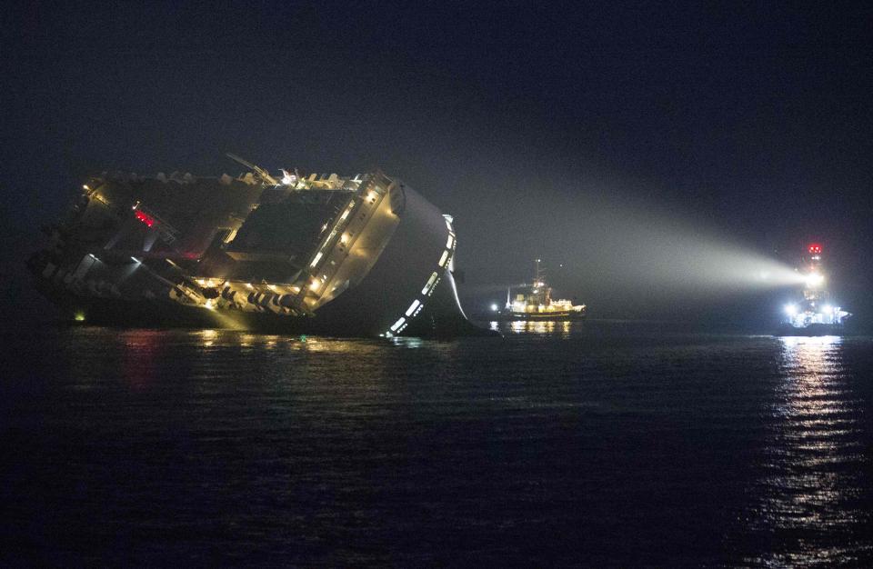 A tug illumnates the cargo ship Hoegh Osaka as it lies on its side after running aground on Saturday evening in the Solent estuary, near Southampton in southern England