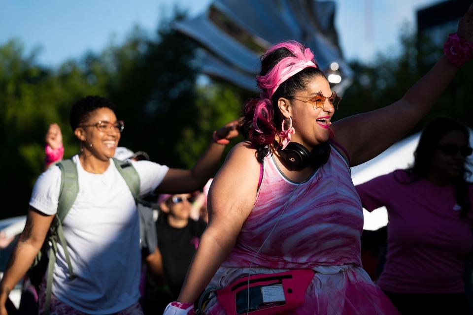 Crystal Ellington, of Blacklick, left, and Natasha Trinity Ford, from southeast Columbus, right, participate in a group dance Saturday before the start of the annual Komen Columbus Race for the Cure, which is back in person, after a two-year absence because of COVID-19.