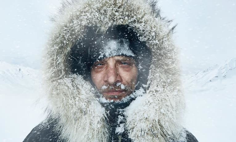 A man in a snowy landscape wearing a Canada Goose coat