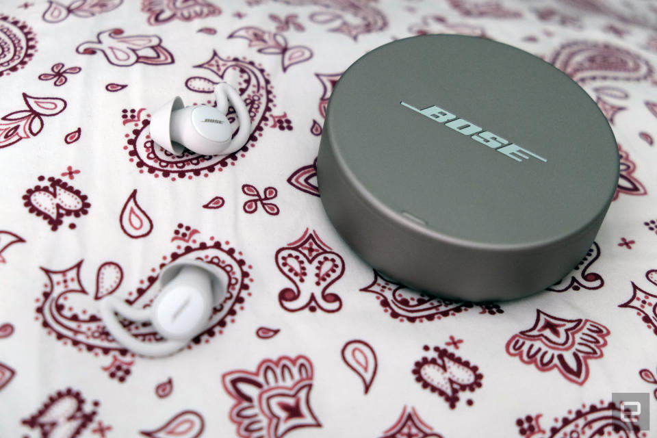 Bose Sleepbuds 2 earbuds with their circular charging case on a patterned tablecloth.