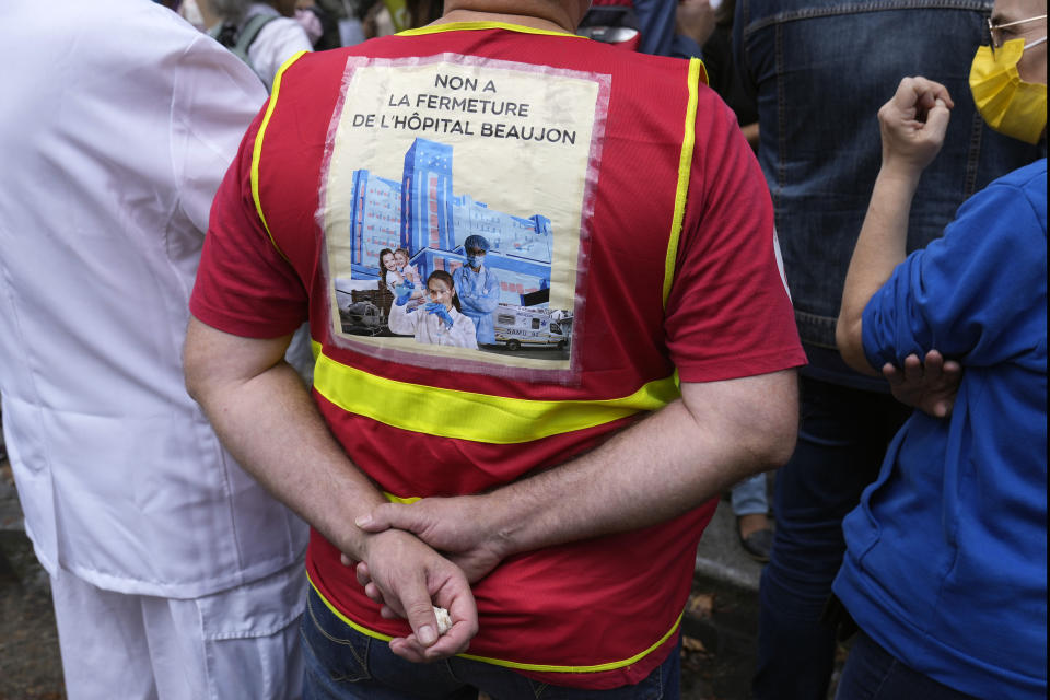 A medical worker holds a placard reading : "No at closing of the Beaujon Hospital", during a protest gathering outside the Health Ministry, in Paris, Tuesday, Sept. 14, 2021 against a law requiring them to get vaccinated by Wednesday or risk suspension from their jobs. The law is aimed at protecting patients from new surges of COVID-19. Most of the French population is vaccinated but a vocal minority are against the vaccine mandate. (AP Photo/Francois Mori)