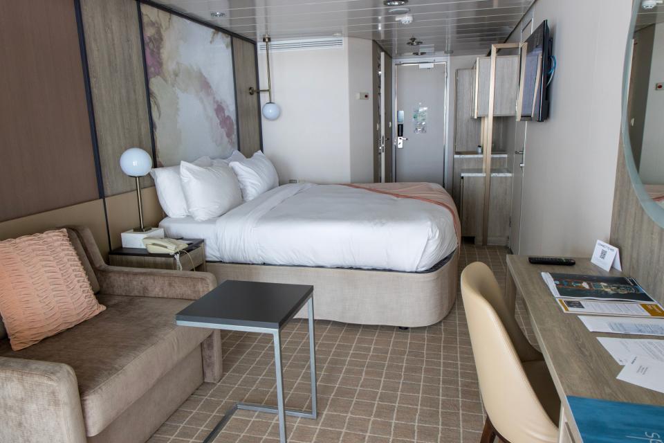 bed in cruise ship room with beige rug next to couch