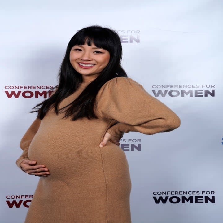 A smiling, pregnant Constance at a media event