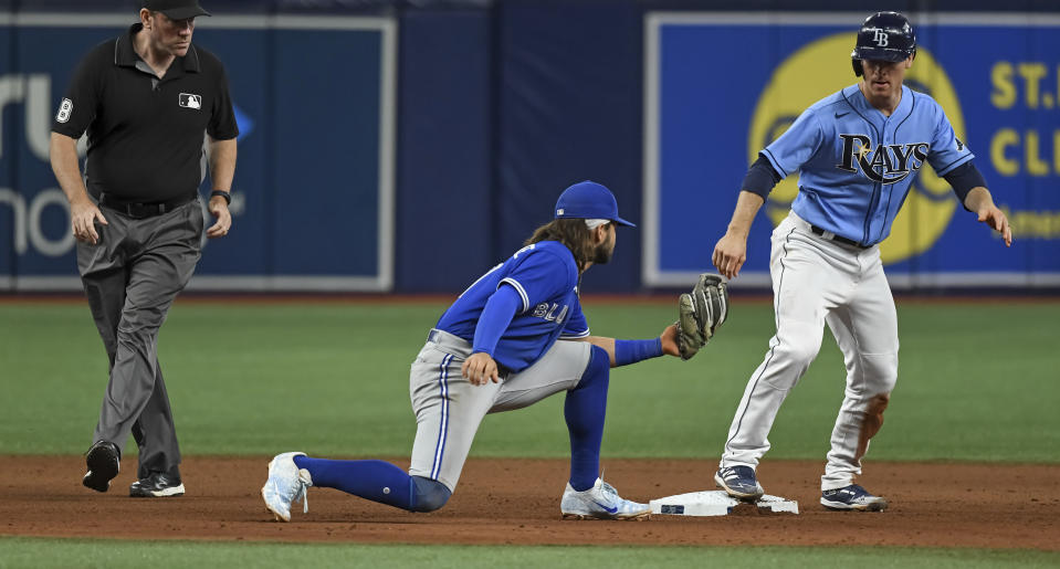 Umpire Chris Conroy, left, watches as Tampa Bay Rays' Joey Wendle, right, stands on second base as Toronto Blue Jays shortstop Bo Bichette is late with the tag during the seventh inning of a baseball game Friday, July 9, 2021, in St. Petersburg, Fla.(AP Photo/Steve Nesius)