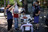 Customers buy fruits from a street vendor at a fruit stall set up outside a residential compound in Beijing