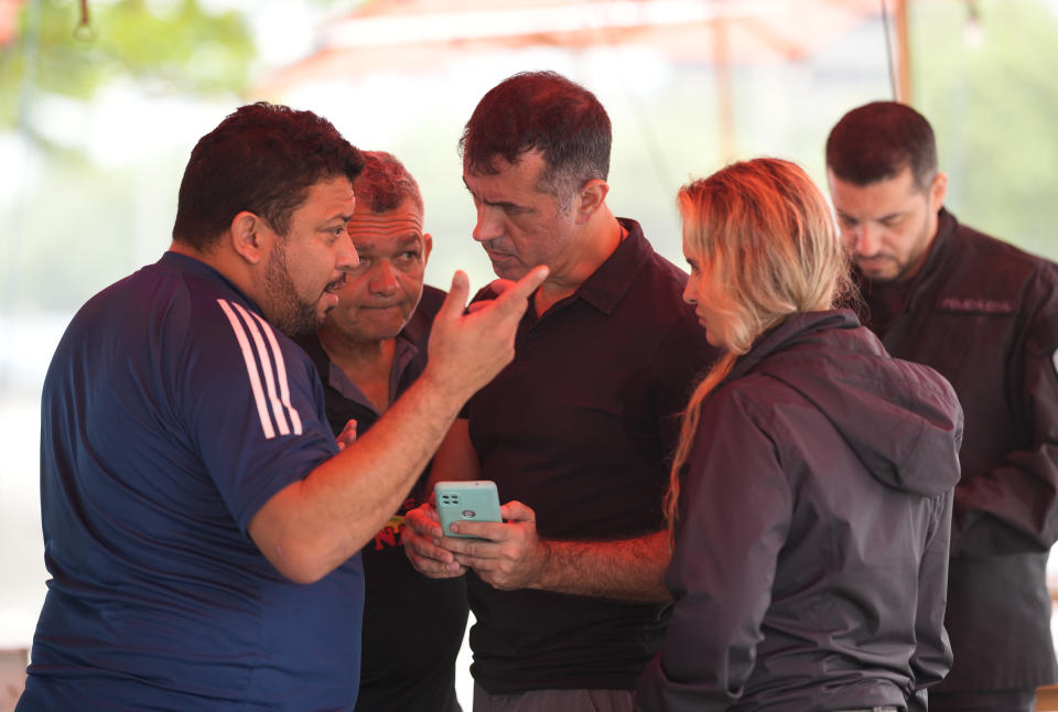 Police speak to workers at the food and bar kiosk "Nana 2" where four doctors were shot, on the beach in the Barra de Tijuca neighborhood of Rio de Janeiro, Brazil, Thursday, Oct. 5, 2023. Three of the doctors died in the overnight shooting. (AP Photo/Silvia Izquierdo)