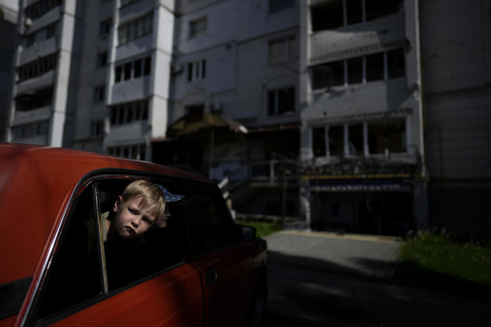 Children wait in a car for their relatives in front of a building destroyed by attacks, in Borodyanka, on the outskirts of Kyiv, Ukraine, Tuesday, May 31, 2022. (AP Photo/Natacha Pisarenko)